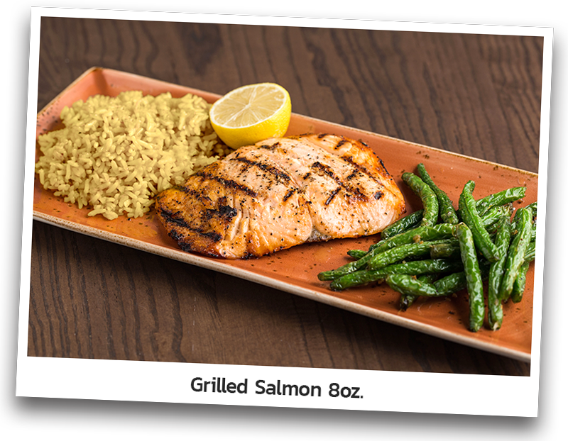 Tender flame grilled salmon lightly seasoned with a touch of garlic butter. Served with rice and seared green beans and presented on a rectangular plate.