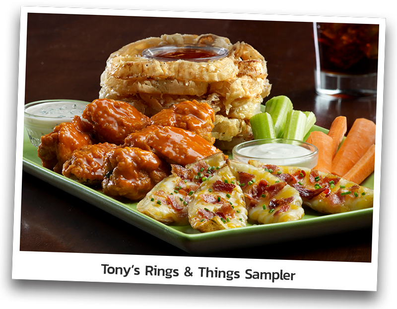 Picture of a platter that includes Onion Loaf, tossed buffalo wings, four potato skins topped with a blend of melted cheeses, bacon and chives, carrot and celery sticks, Sour Cream and Ranch dressing as sides.